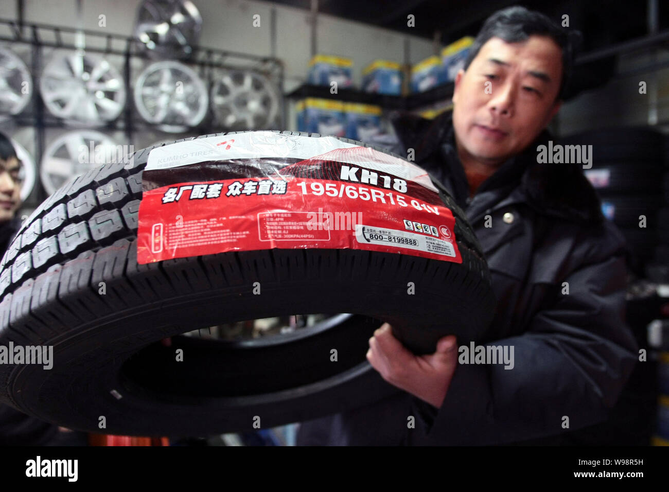 Un travailleur chinois montre un pneu de pneus Kumho Co. à un marché de  pièces d'automobile à Shanghai, Chine, 21 mars 2011. Fabricant de pneus sud- coréen Kumho Tyres Co Photo Stock -