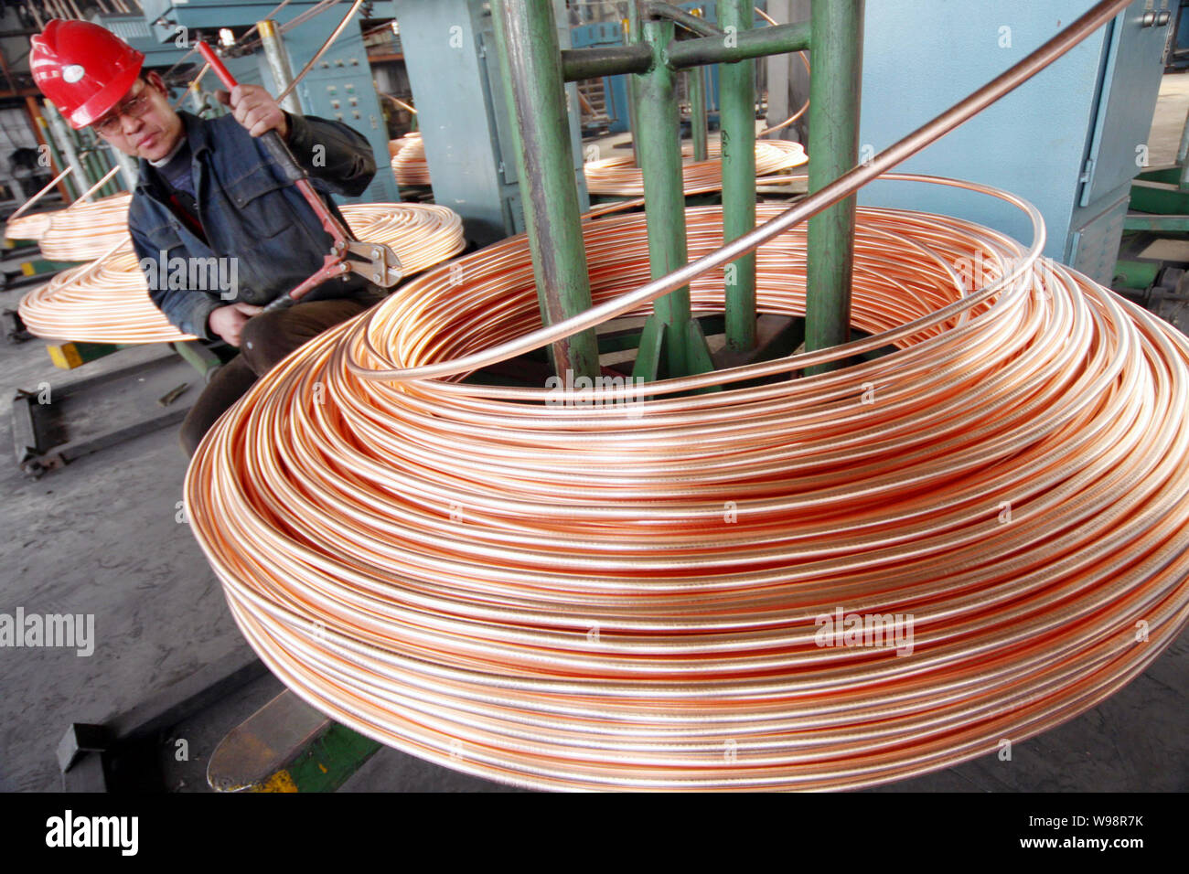 Un travailleur chinois bobines palans de tubes en cuivre à une usine de produits en cuivre à Nantong ville, province de Jiangsu, Chine de l'Est, le 12 mars 2011. Rose de cuivre Banque D'Images