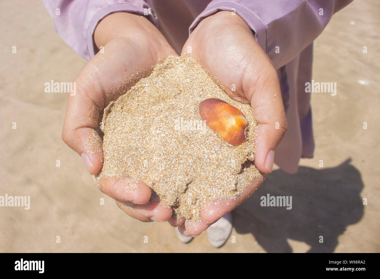 Tenir la mer fille blanc sable avec une coquille d'Orange Banque D'Images