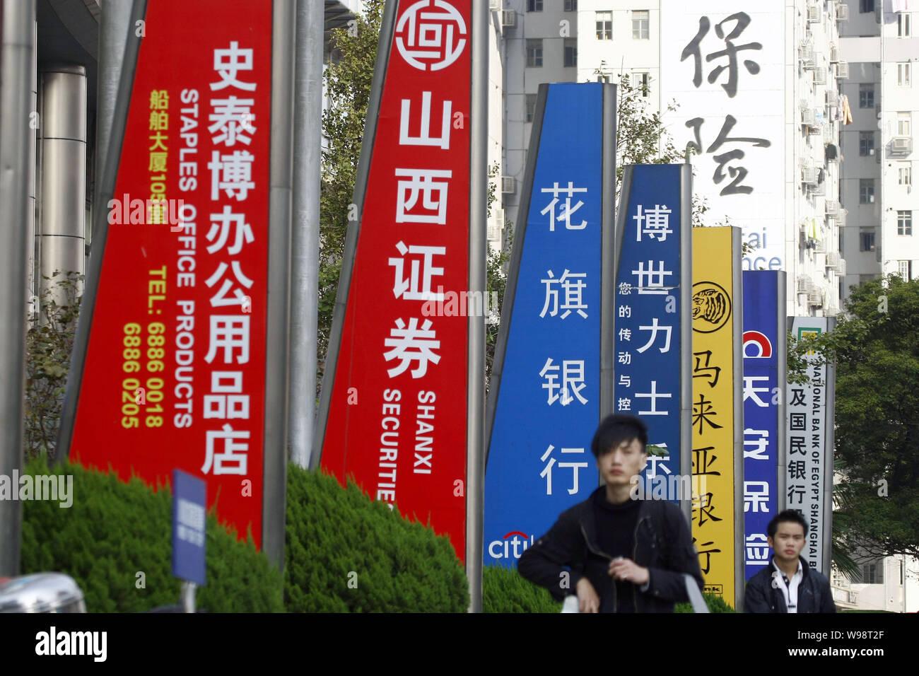 --FILE--Local des résidents chinois passent devant les enseignes, des affaires et des sociétés chinoises dans le quartier financier de Lujiazui à Pudong, Shanghai, Chine, 2 Banque D'Images