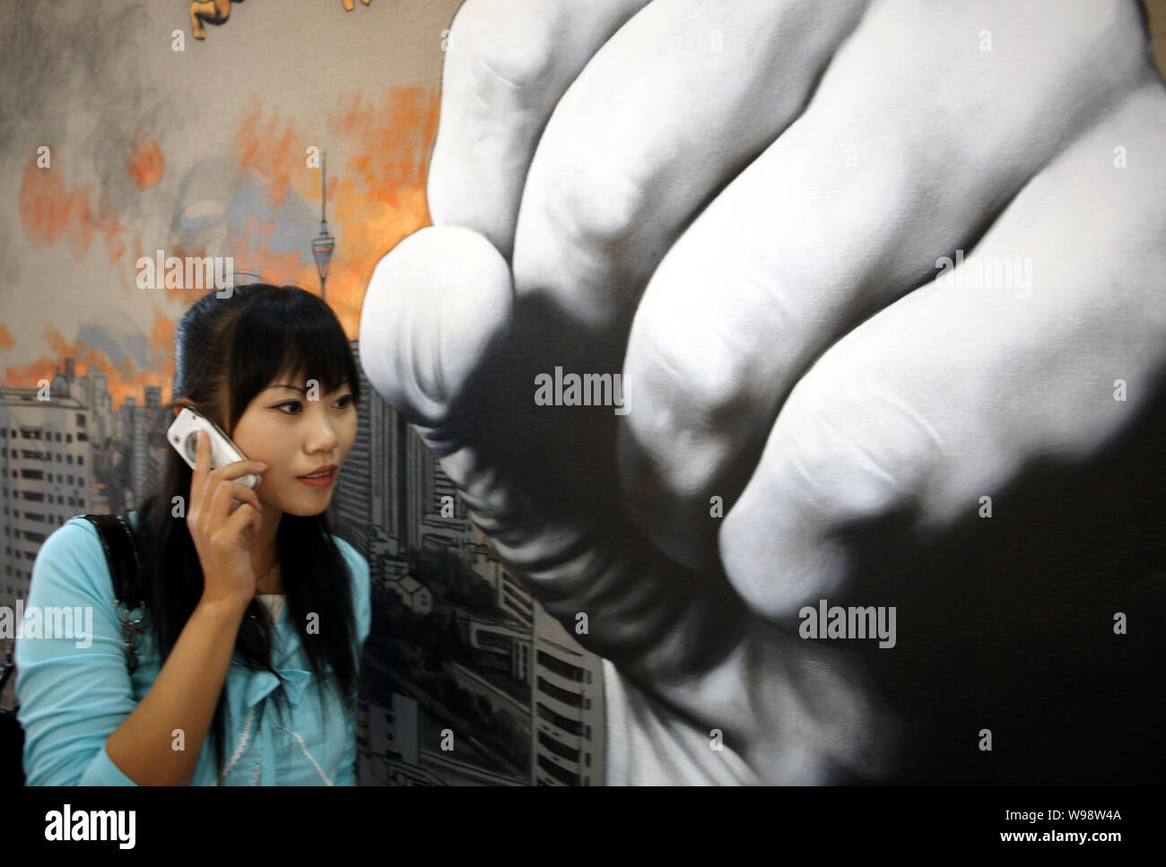 --FILE--une jeune femme chinoise à parler sur son téléphone portable passe devant une affiche avec un coup de poing à Beijing, Chine, 7 septembre 2008. Chaque mobile de Beijing Banque D'Images