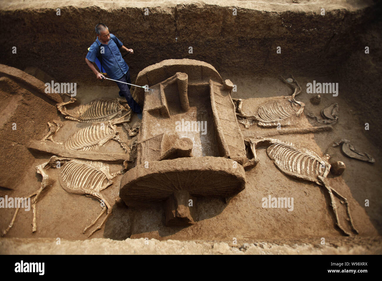 Le personnel d'un opérateur arrose afin de maintenir l'humidité des restes de chars et de chevaux de l'Est de dynastie Zhou (770BC-221BC) découvert dans le centre de la Chine, Banque D'Images