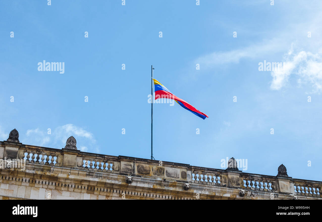 Jaune, Bleu et rouge striped drapeau colombien vole au-dessus d'un bâtiment public à Bogotá, Colombie sur une journée ensoleillée Banque D'Images
