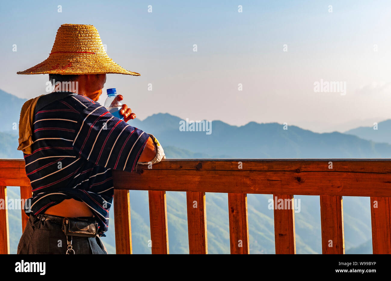 Un homme de la minorité autochtone Zhuang regardant le paysage de montagne dans la région de Ping An après une dure journée de travail, Longsheng county, Guangxi, Chine. Banque D'Images