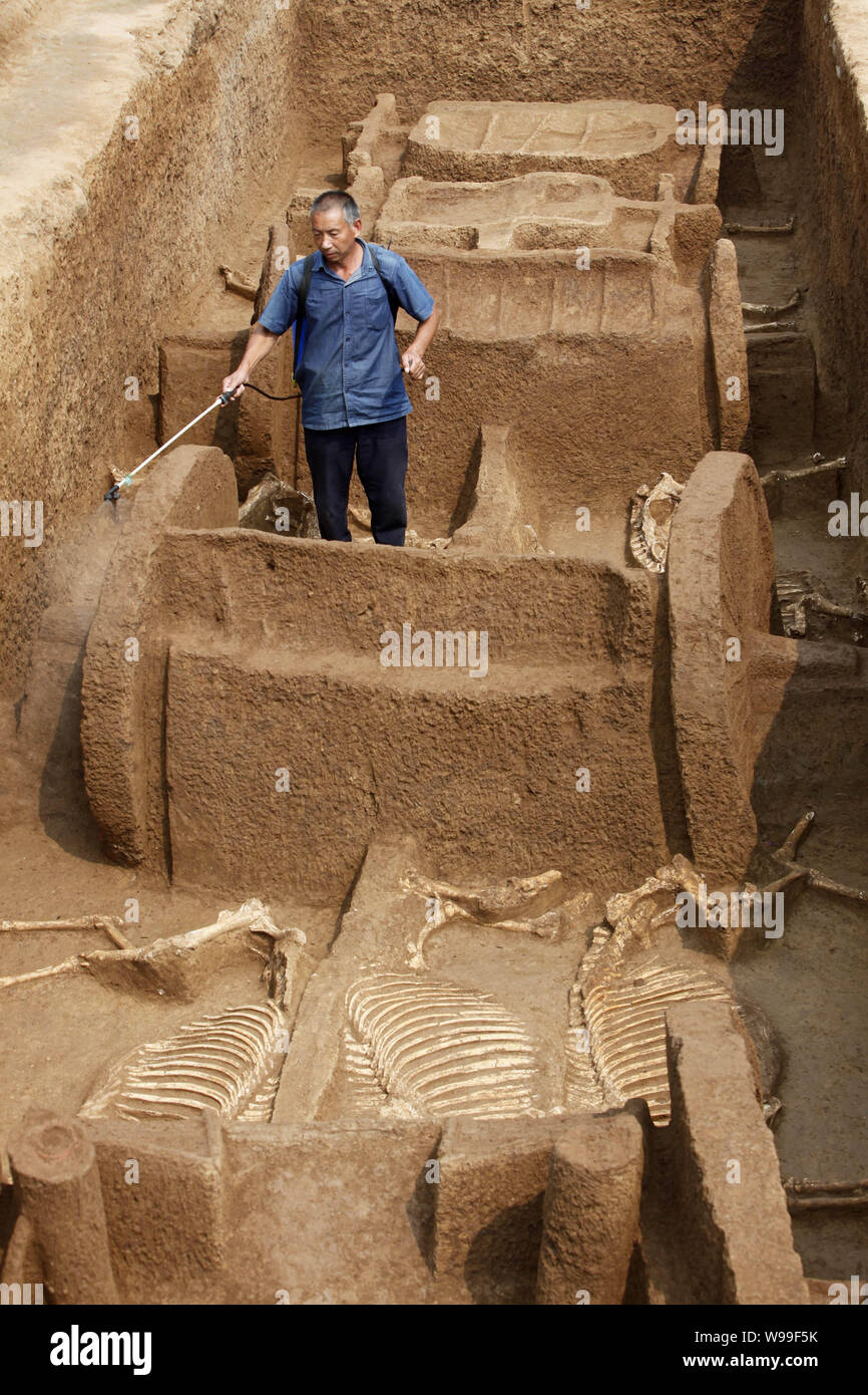 Le personnel d'un opérateur arrose afin de maintenir l'humidité des restes de chars et de chevaux de l'Est de dynastie Zhou (770BC-221BC) découvert dans le centre de la Chine, Banque D'Images