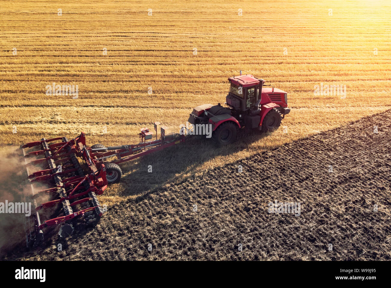 Machine agricole la récolte dans les champs. Le tracteur tire sur un mécanisme pour la fenaison. La récolte en automne le matin à l'aube dans l'agroalimentaire. Banque D'Images