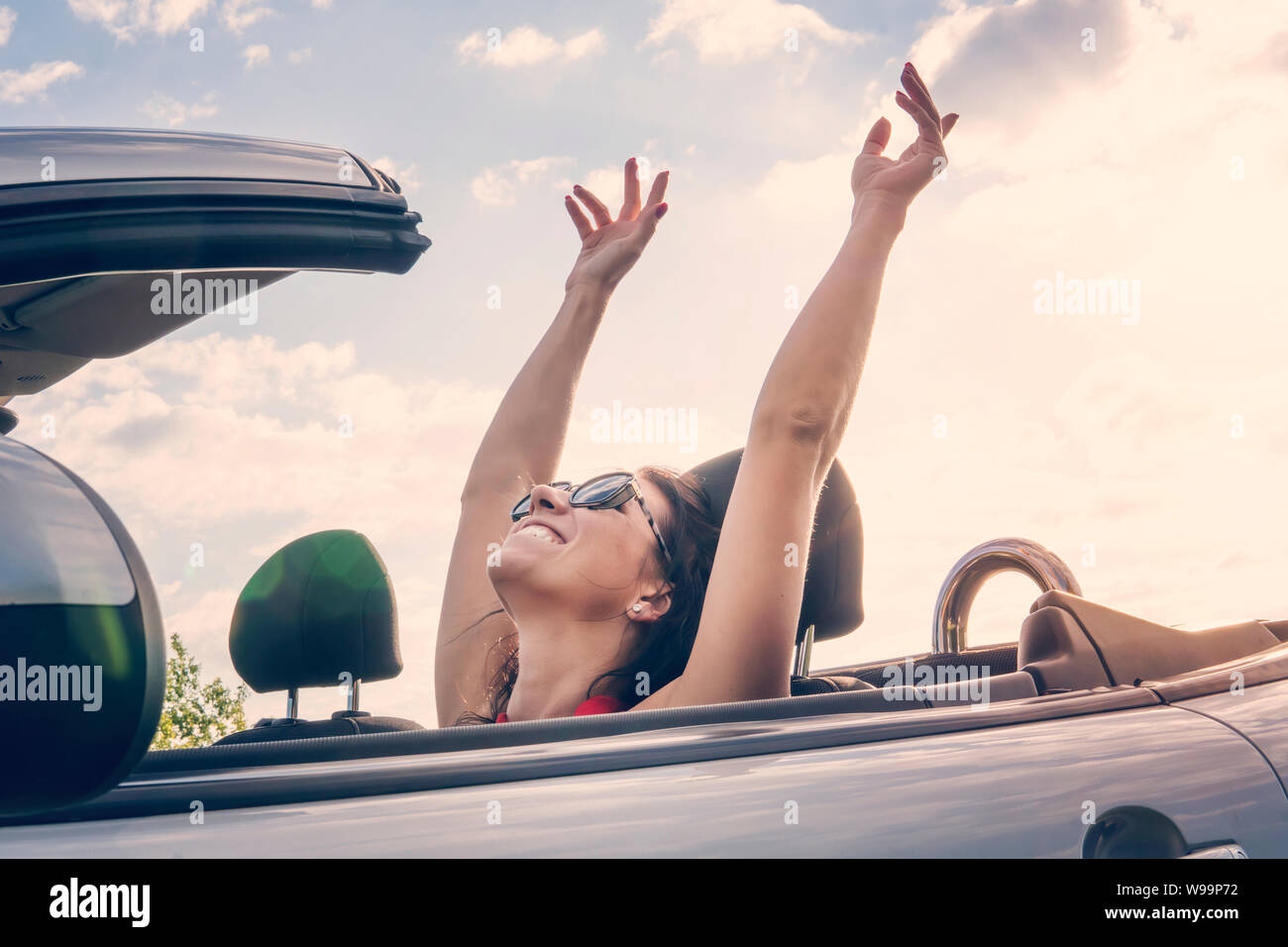 Happy girl relaxing profitant du soleil assis en voiture décapotable sur la route des vacances d'été voyage en voiture sur le voyage. Liberté femme concept sentiment Banque D'Images