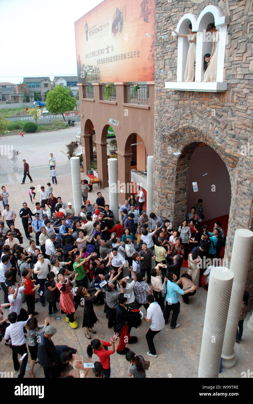 Une foule de personnes essayer de saisir les factures RMB étant dispersées par des jeunes femmes de la deuxième étage d'une villa lors d'un événement promotionnel pour une pr Banque D'Images