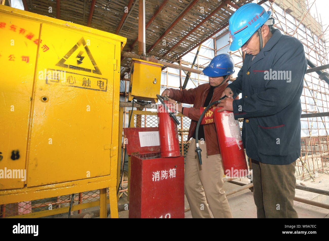 Les travailleurs chinois vérifier les extincteurs et autres équipements de protection incendie sur un chantier de construction au cours d'une inspection de sécurité-incendie à Shanghai, Banque D'Images