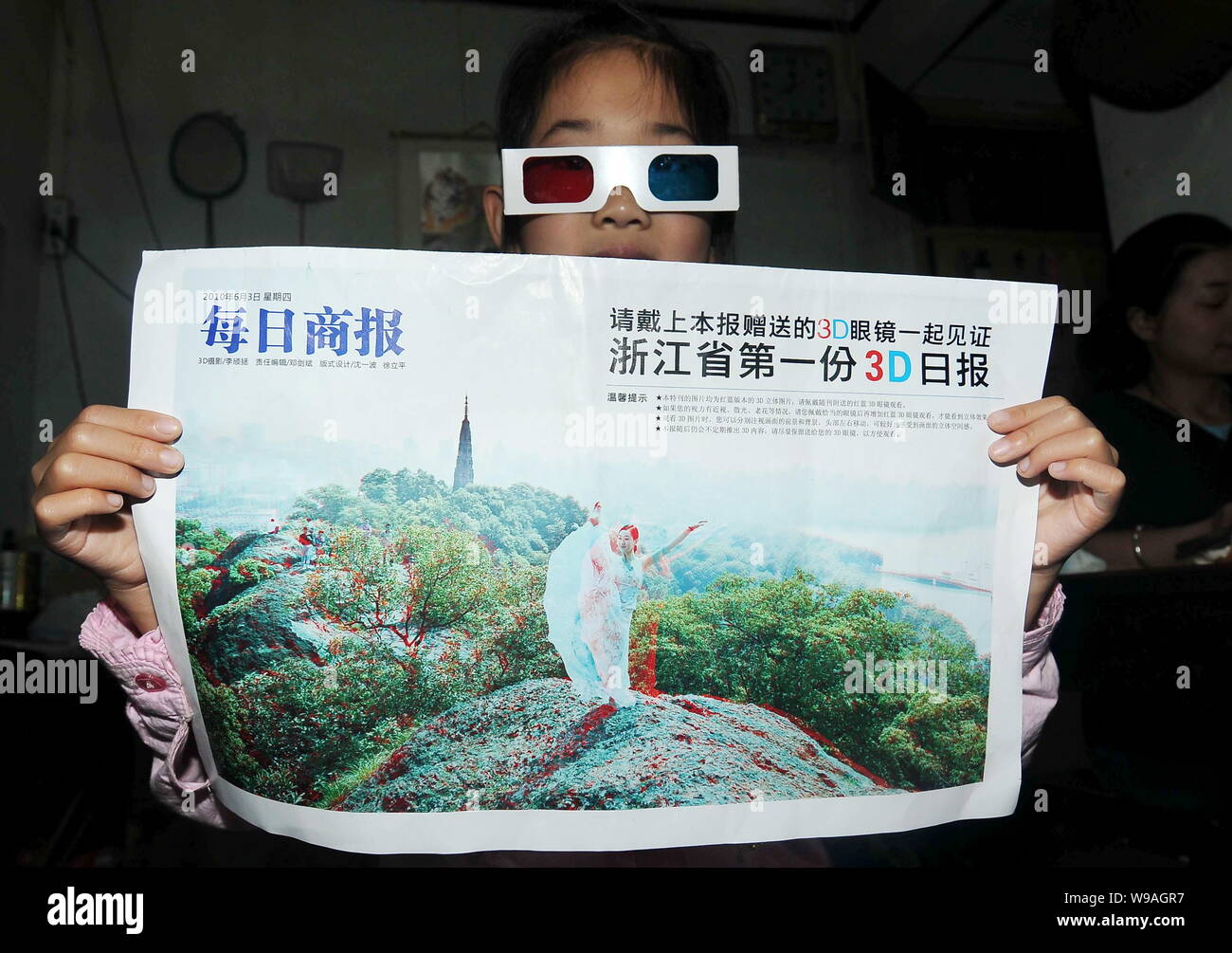 Une jeune Chinoise portant des lunettes 3D montre la 3 édition du journal d'affaires quotidiennes dans la ville de Hangzhou, province de Zhejiang, Chine de l'est 3 juin 2010. A l Banque D'Images