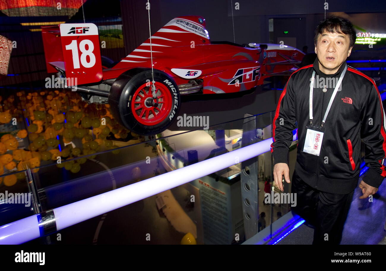 Superstar kungfu Hong Kong Jackie Chan passe devant une voiture de course à l'intérieur du pavillon de l'huile dans le monde site de l'Expo de Shanghai, Chine, 13 mai 2010. Jacki Banque D'Images Superstar kungfu Hong Kong Jackie Chan passe devant une voiture de course à l'intérieur du pavillon de l'huile dans le monde site de l'Expo de Shanghai, Chine, 13 mai 2010. Jacki Banque D'Images