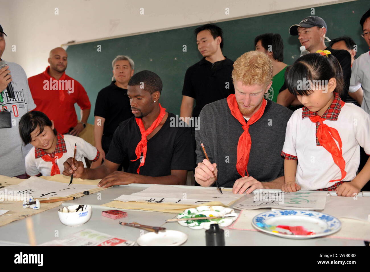 Les joueurs de basket-ball NBA Aaron Brooks (L2) et Chase Budinger (R2) de la Houston Rockets apprendre à écrire le chinois calligraphie à une école primaire pour mig Banque D'Images