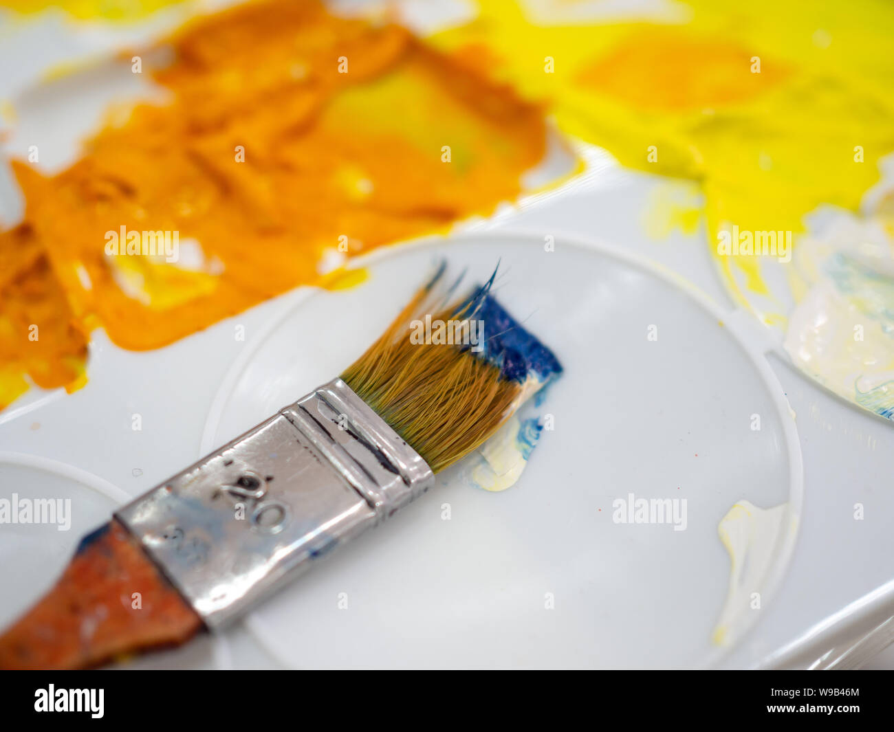 Close-up artiste pinceau sur la palette de l'artiste plastique blanc avec couleur acrylique jaune. Banque D'Images Close-up artiste pinceau sur la palette de l'artiste plastique blanc avec couleur acrylique jaune. Banque D'Images