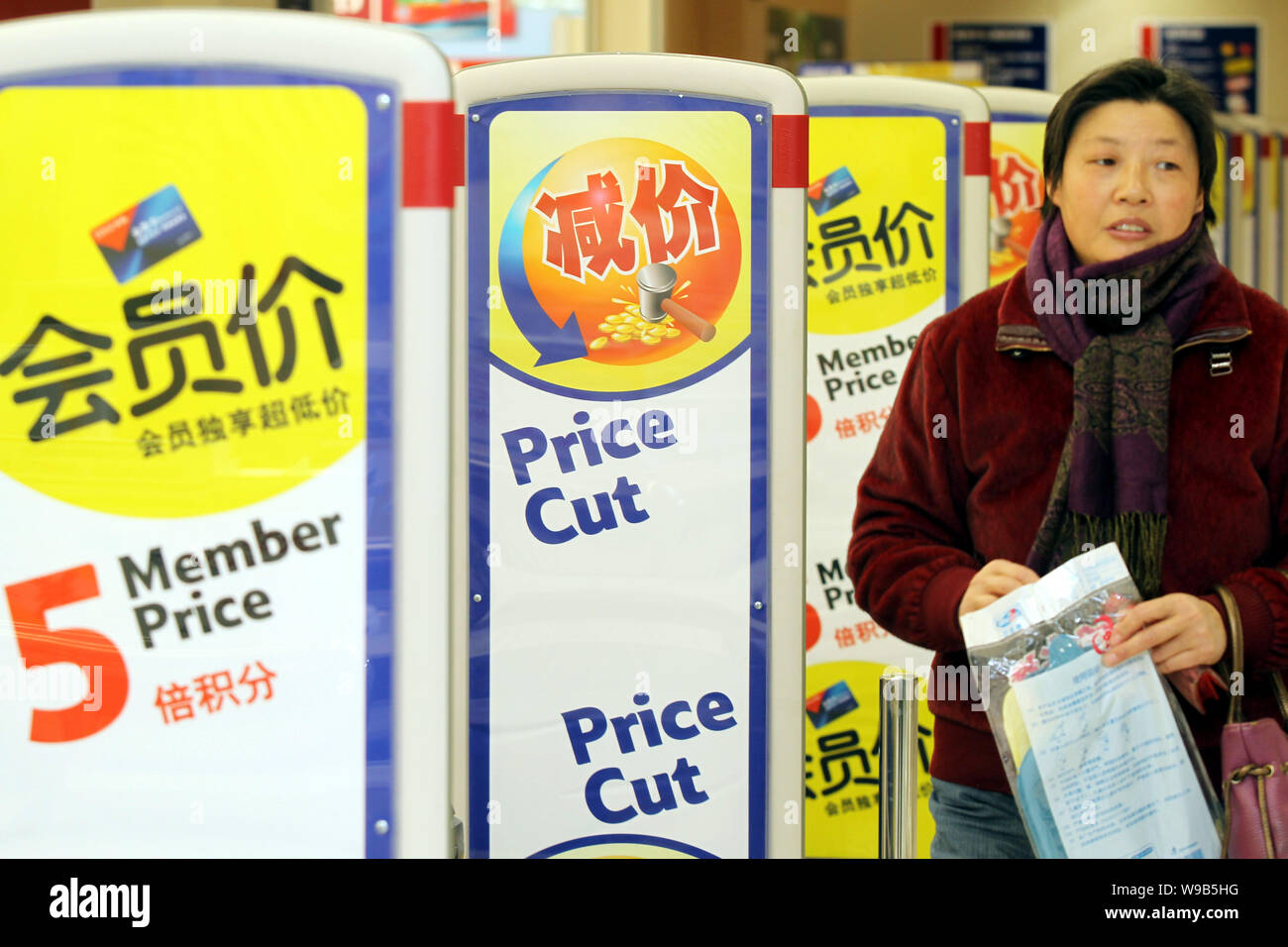 Un client chinois marche dernières affiches pour réduction de prix dans un supermarché dans la ville de Nantong, Chine de l'est de la province de Jiangsu, le 11 décembre 2010. Chines gouvernem Banque D'Images