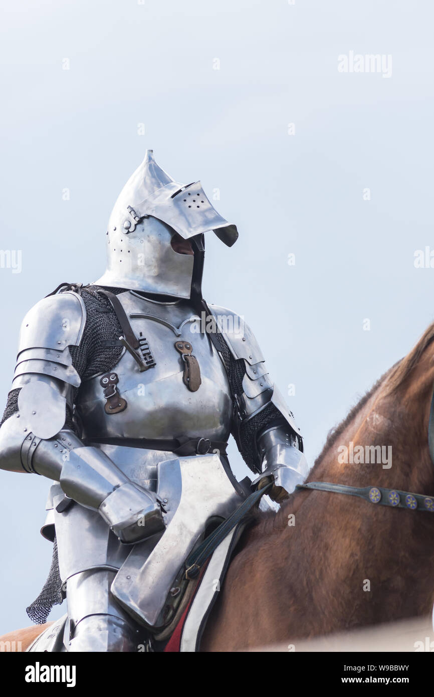 Un homme avec la moitié chevalier casque ouvert équitation un cheval brun  tenant une épée Photo Stock - Alamy