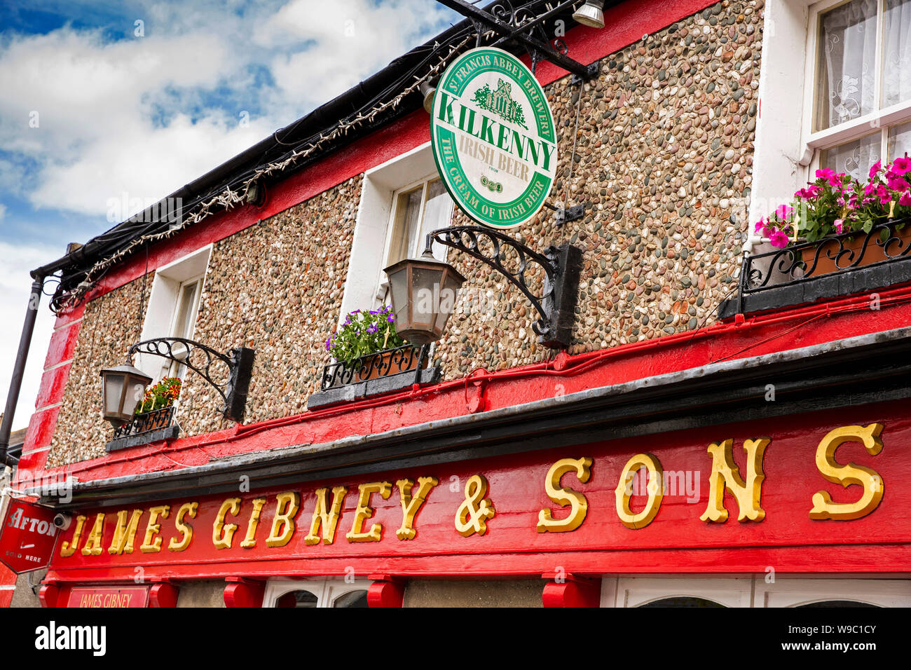 L'Irlande, Co Dublin, Malahide, New Street, James Gibney's pub irlandais traditionnel sign hanging basket et la publicité de la bière Kilkenny Banque D'Images