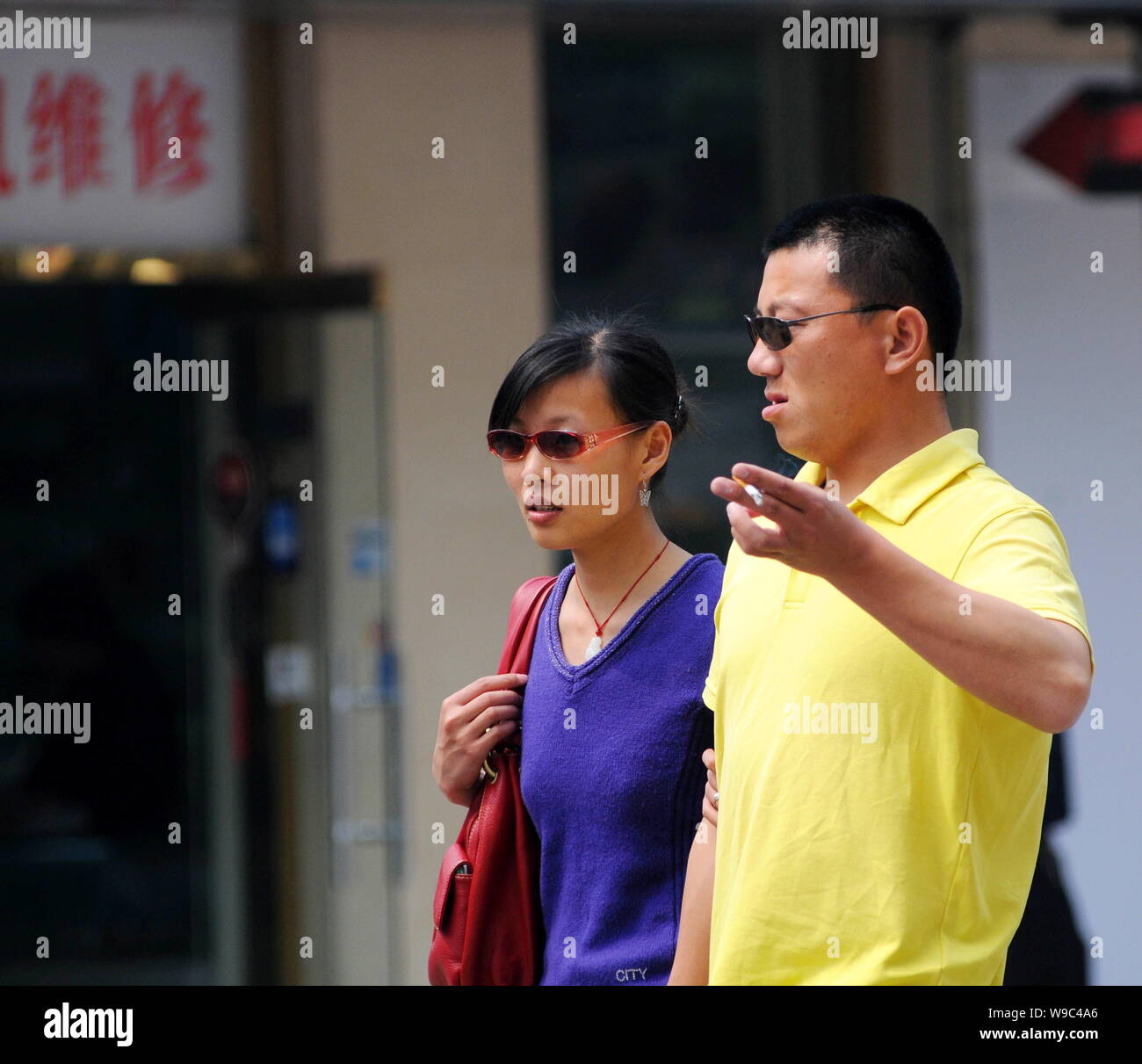 --FILE--un Chinois fume en marchant avec une femme dans une rue de Beijing, Chine, 15 avril 2008. Liu Zejun, le directeur de l'Aiguo Beijing nous Banque D'Images