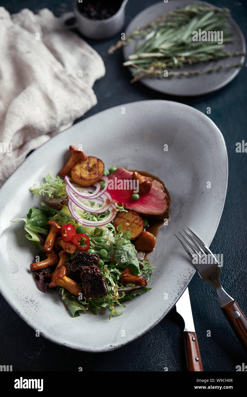 Tagliata de boeuf avec légumes. Close-up, clé faible, fond gris. Banque D'Images