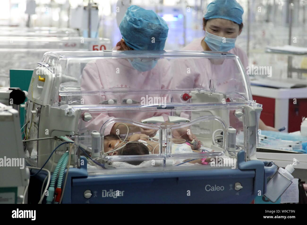 Les infirmières chinois assister à la naissance des soeurs jumelles siamoises conservés dans un incubateur à l'Hôpital pour enfants de Bayi de Beijing, Chine, le jeudi, 13 août 2009 Banque D'Images