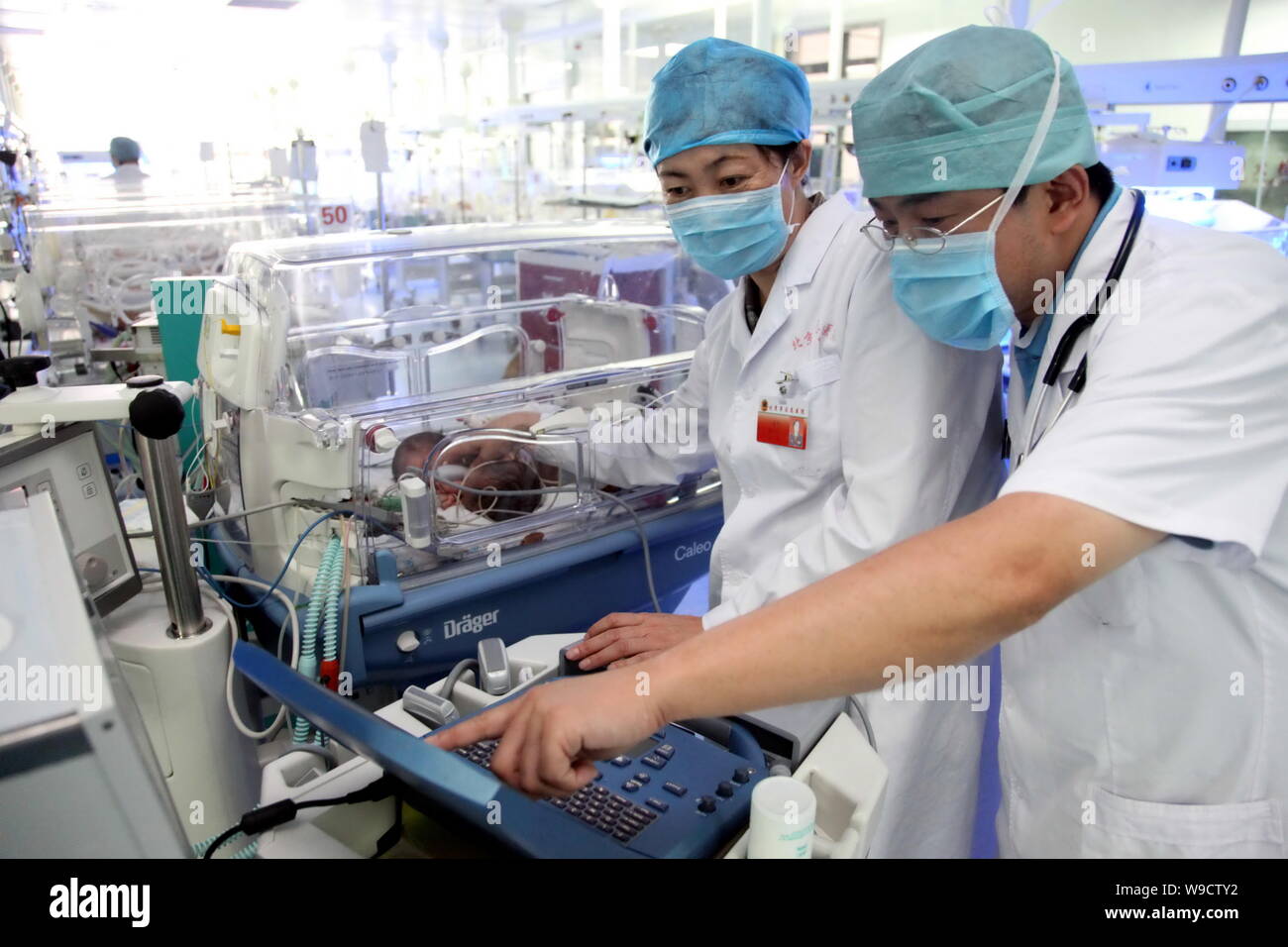 Les médecins chinois examiner le nouveau-né des soeurs jumelles siamoises conservés dans un incubateur à l'Hôpital pour enfants de Bayi de Beijing, Chine, le jeudi, 13 août 20 Banque D'Images