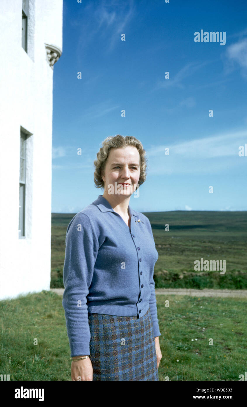 Ecosse, Royaume-Uni: Un vieux film de couleur d'une dame dans une jupe tartan, à côté d'un bâtiment blanc. Cela a été pris entre 1950 et 1970. Banque D'Images