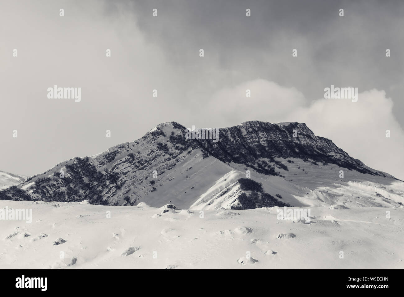 Le mont enneigé avec plage et forêt du soleil pente avec des pierres couvertes de neige. Montagnes du Caucase en hiver, Shahdagh, Azerbaïdjan. T rétro noir et blanc Banque D'Images