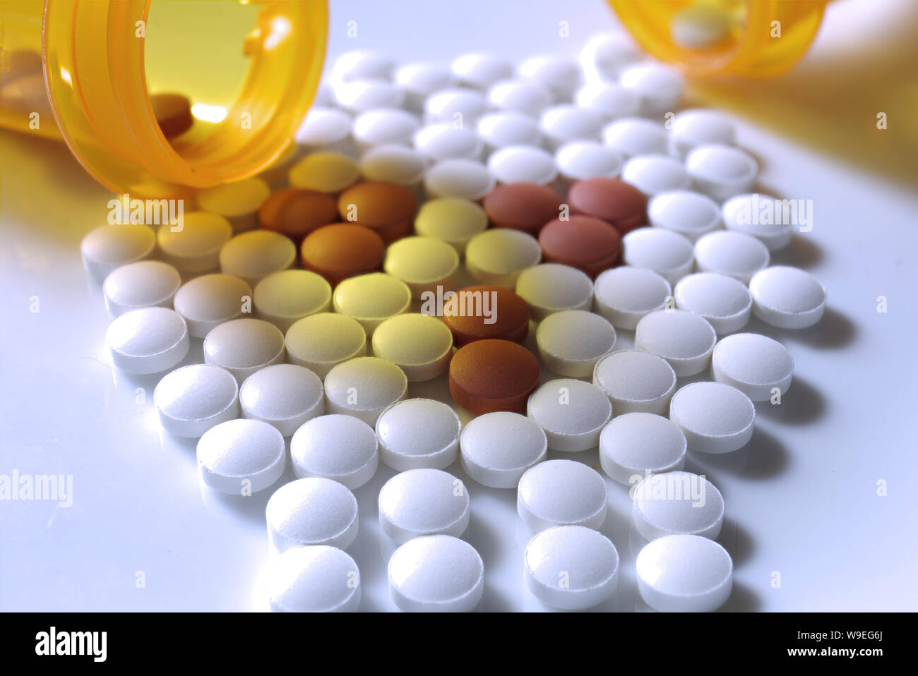 Deux flacons de prescription qui se répandent des pilules de différentes couleurs dans un crâne grossièrement formé. Banque D'Images