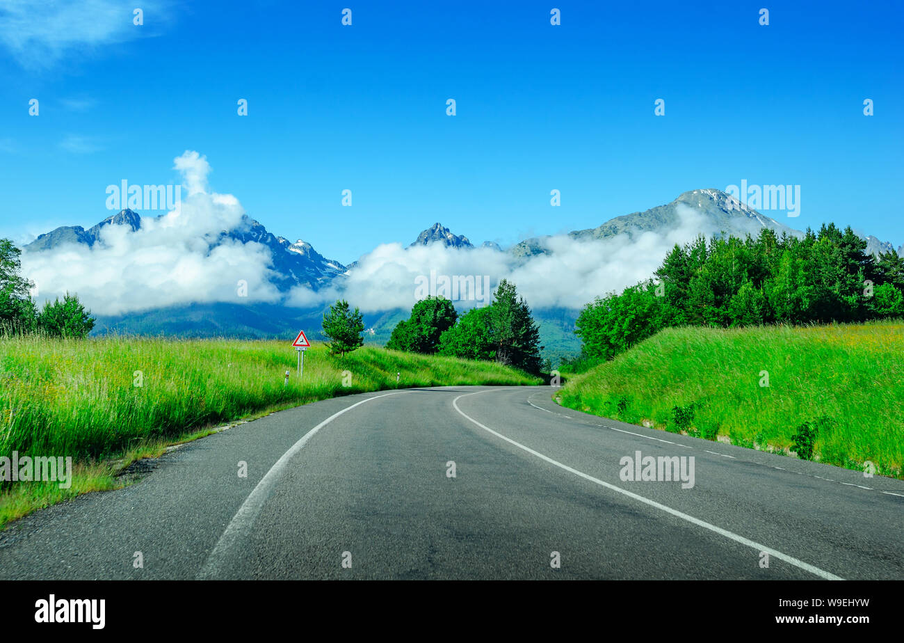 Route asphaltée entre les champs sur fond d'un paysage de montagne. Banque D'Images