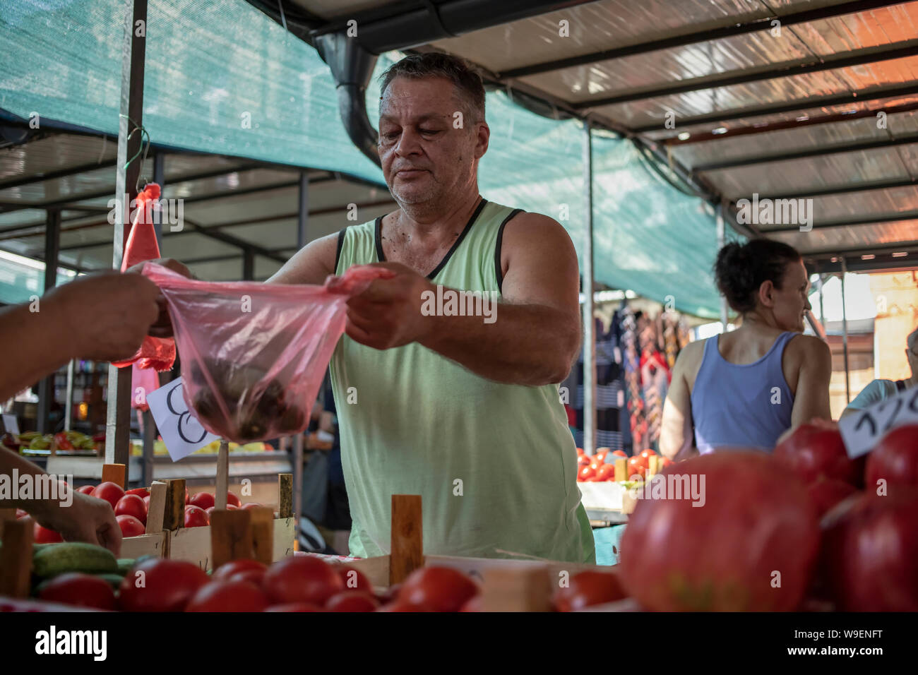 Belgrade, Serbie, 13 juillet 2019 : Un vendeur de légumes avec les clients au marché vert Zemun Banque D'Images