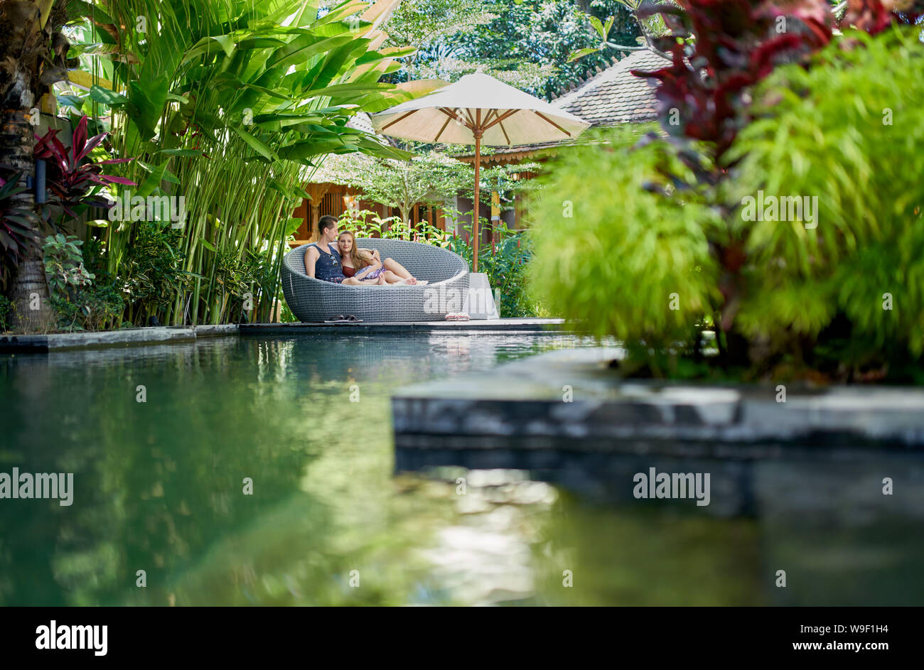 Coup franc de young caucasian couple se prélasser dans la piscine de luxe moderne chaise près de tropical Hotel and Spa à Bali Banque D'Images