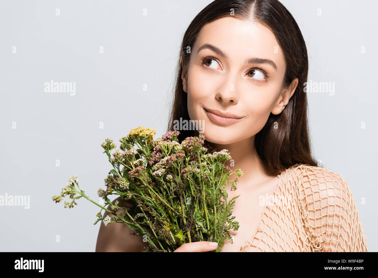 Belle femme en maille beige avec des fleurs sauvages à l'écart isolé sur gray Banque D'Images