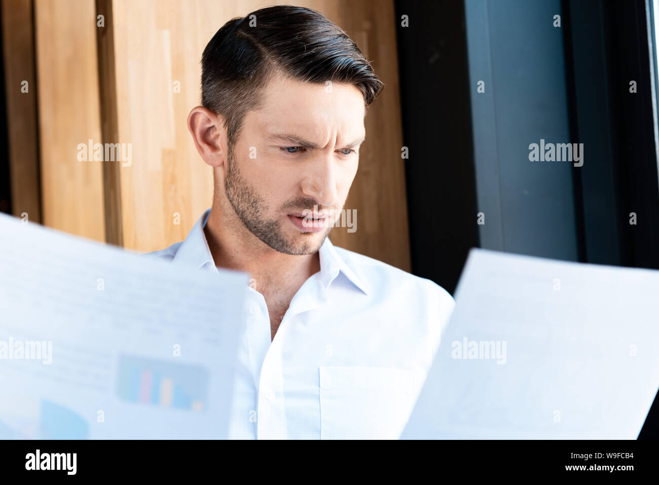 L'homme confus en chemise blanche à la recherche de documents à Banque D'Images