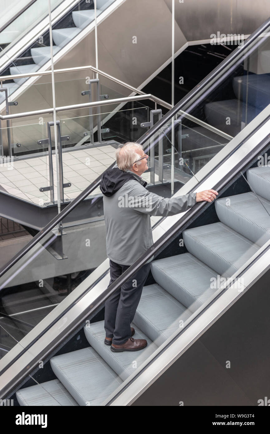 A Middle aged man riding un seul escalator Banque D'Images