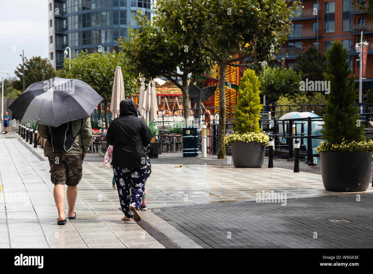 Un couple en train de marcher sous la pluie, la dame tient un parapluie Banque D'Images