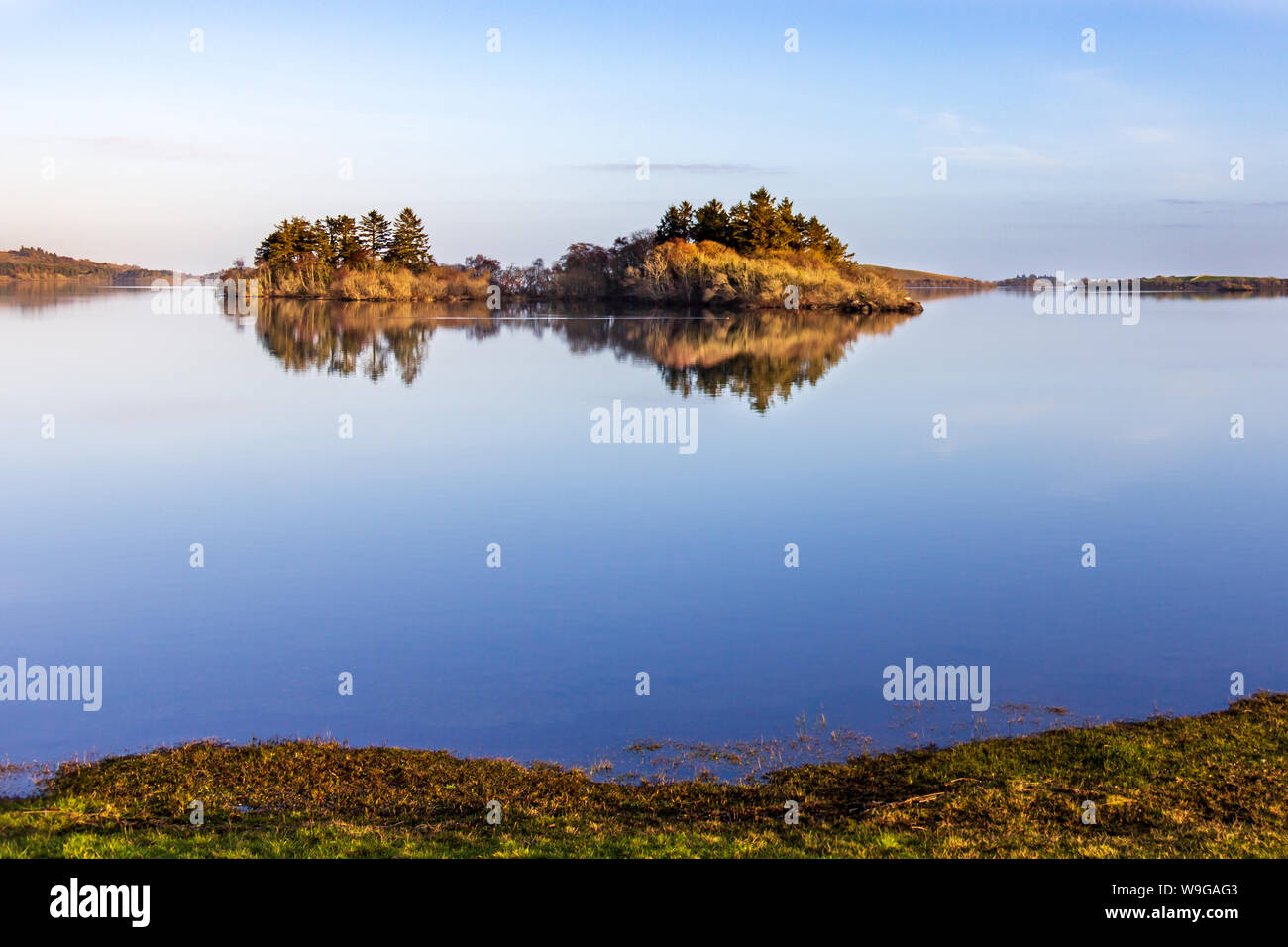 Dans les eaux calmes du lac Lough Corrib, comté de Galway, en Irlande, est le reflet d'une vue sur les collines environnantes et les îles au coucher du soleil Banque D'Images