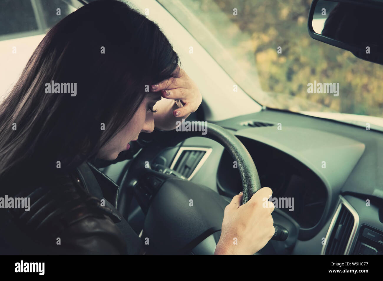 L'anxiété sentiment pilote femme derrière le volant. Close up of crying girl sitting intérieur véhicule et de pleurer. Femme pilote de tête estimé et maladie Banque D'Images