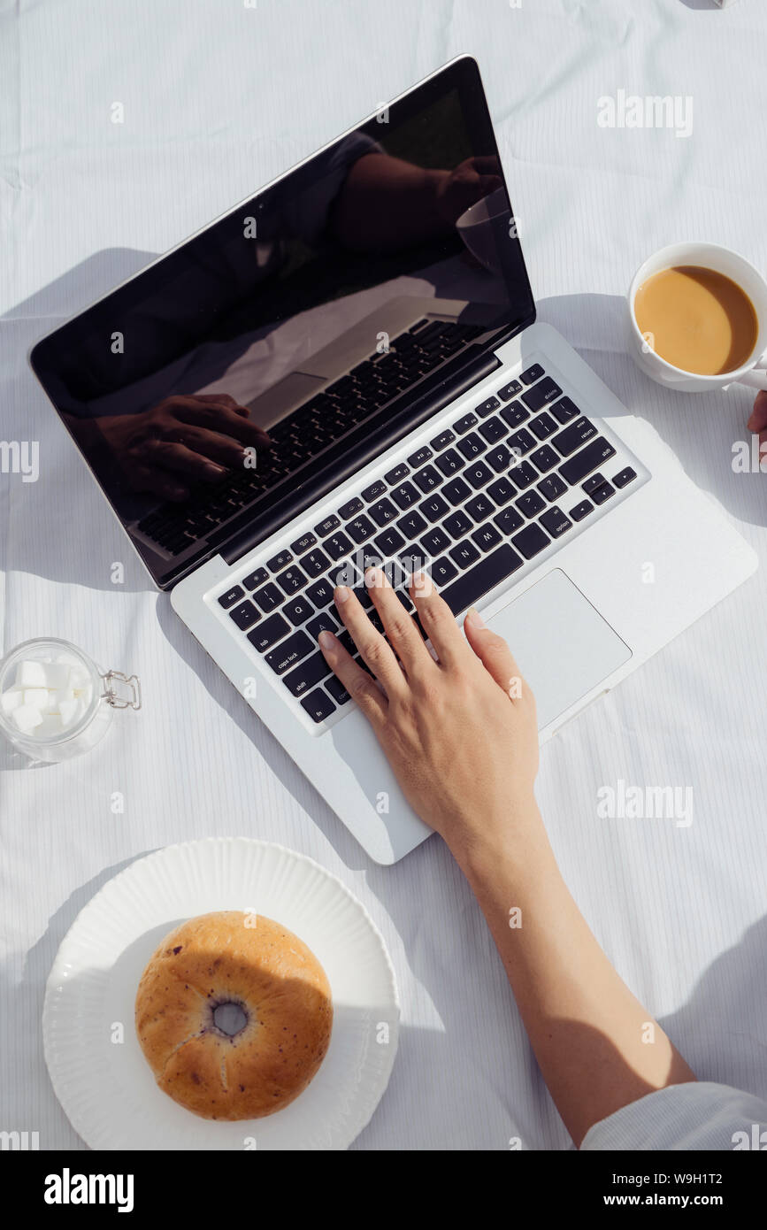 L'homme les mains sur le clavier d'ordinateur portable et le café avec anneau. Un travail facile, style de vie à la maison le matin. Banque D'Images