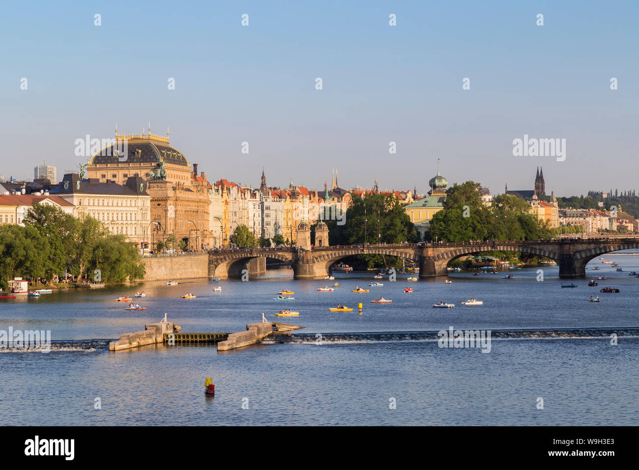 Vue sur le pont de la Légion, le Théâtre National et d'autres vieux bâtiments et les gens sur le bateau à pédales sur la rivière Vltava à Prague, République tchèque. Banque D'Images