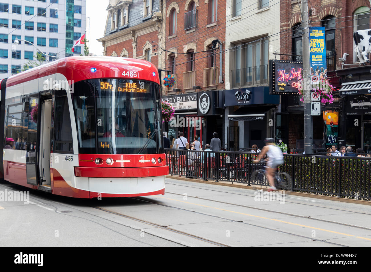 TTC Streetcar au centre-ville le quartier des divertissements de Toronto avec les cyclistes de passage. Banque D'Images