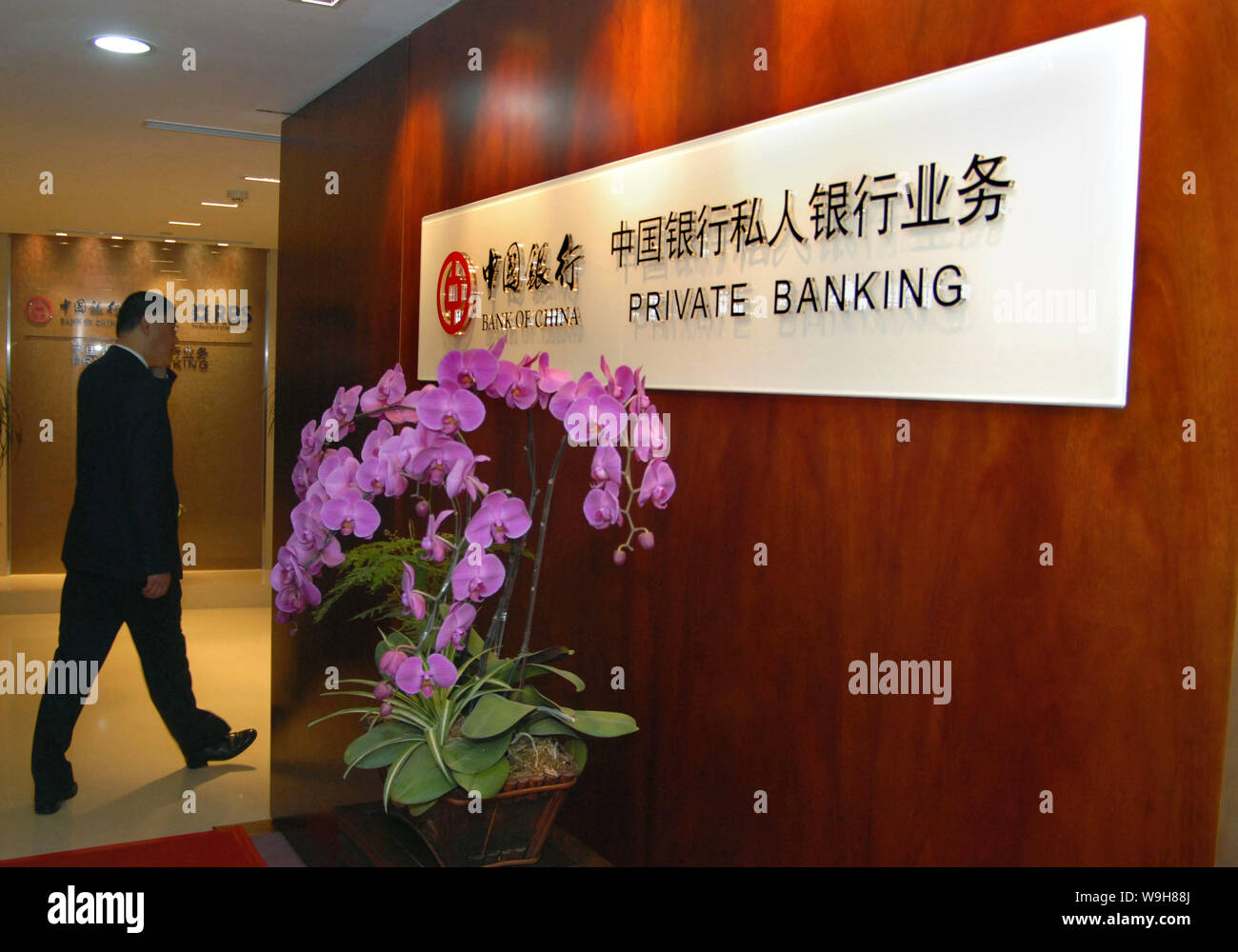 Un homme marche par une pancarte de Banque Privée Banque de Chine lors de la cérémonie d'ouverture des services de banque privée par la Banque de Chine (BOC) et la Roya Banque D'Images