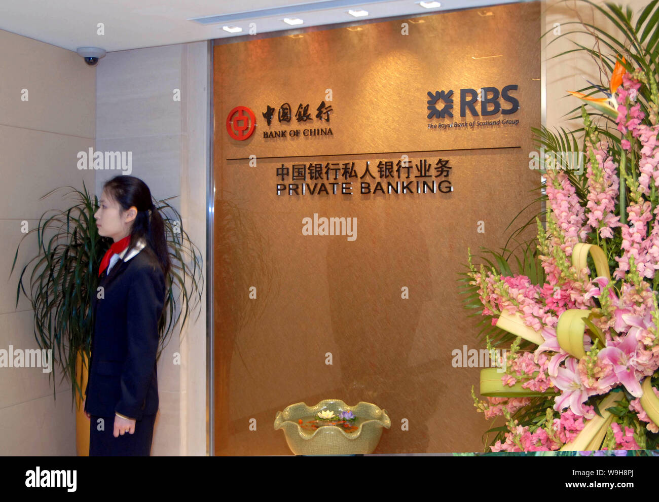 Un employé de banque chinoise se trouve près de la pancarte du Private Banking offerts par la Banque de Chine et la RBS, à la cérémonie d'ouverture de la banque privée ser Banque D'Images