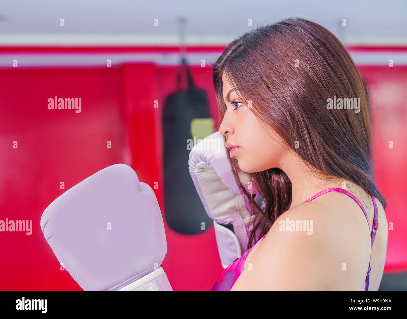 Superbe femme aux cheveux noirs en gants de sport pour l'entraînement de boxe dans la salle de sport. Banque D'Images