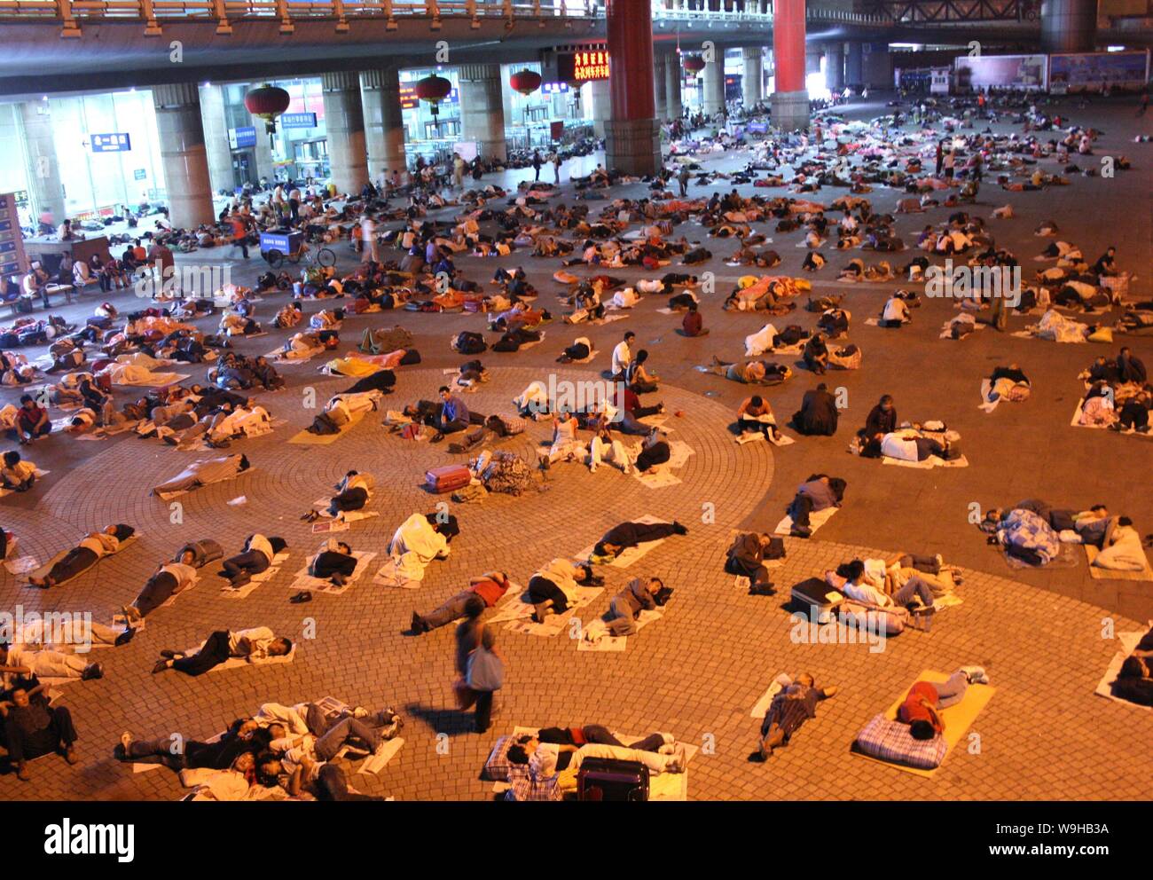 Des foules de passagers reste sur le sol d'une place en face de la gare ouest de Beijing à Beijing le 4 juillet 2007. Les flux de passagers demeurent à des Banque D'Images