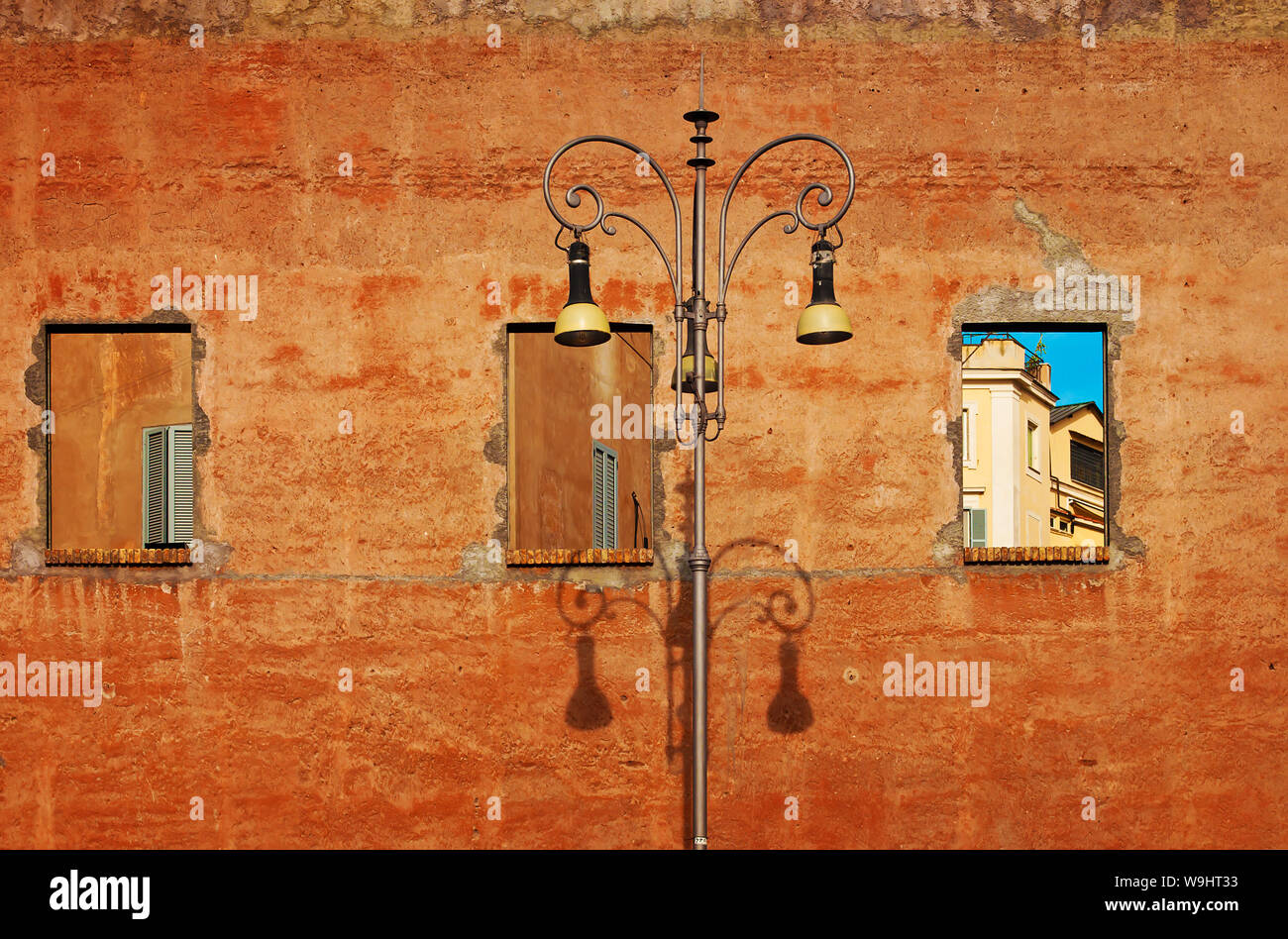 Trois trous sur un mur jaune, ciel bleu et les fenêtres avec volets gris. High street lamp. Rome, Italie Banque D'Images