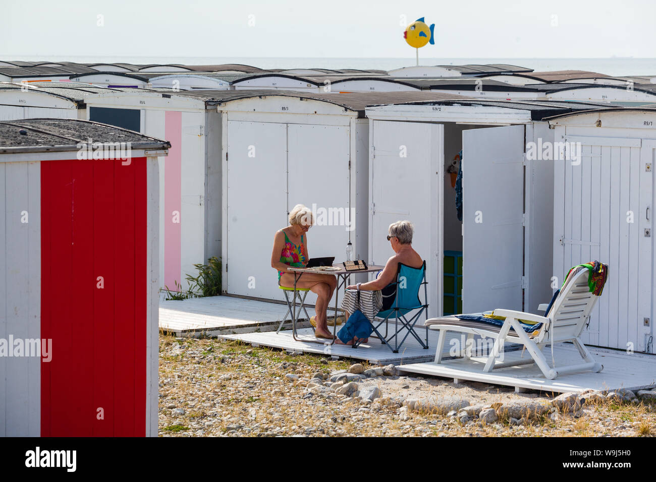 Un couple de femmes jouer un jeu de Rami en dehors de leurs cabanes de plage sur le front de mer dans le Havre, Normandie, France Banque D'Images