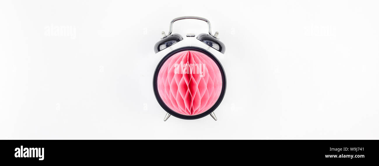 Anniversaire ou d'invitation de partie de douche de bébé modèle. Réveil noir avec boule de papier nid d'rose sur fond blanc. Haut Conception créative Banque D'Images