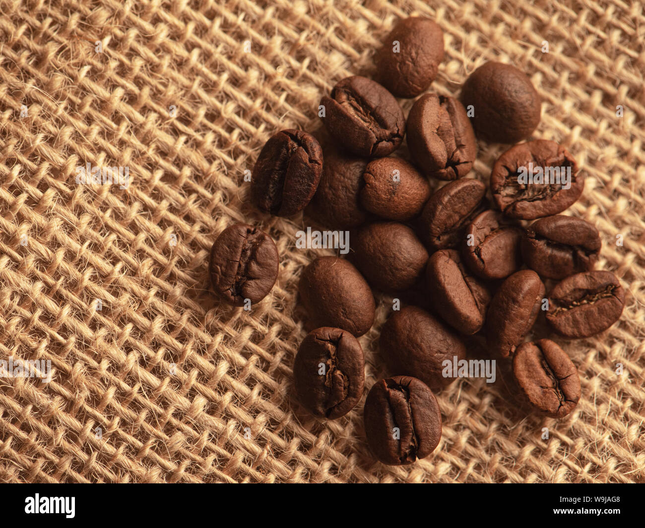 Les grains entiers de café noir sur la toile de jute. Banque D'Images