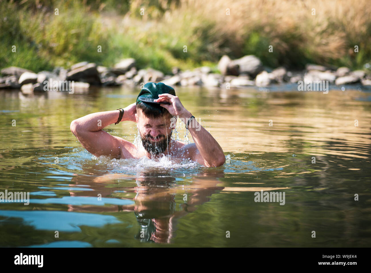 L'homme en cours de refroidissement dans une rivière sur une chaude journée d'été Banque D'Images