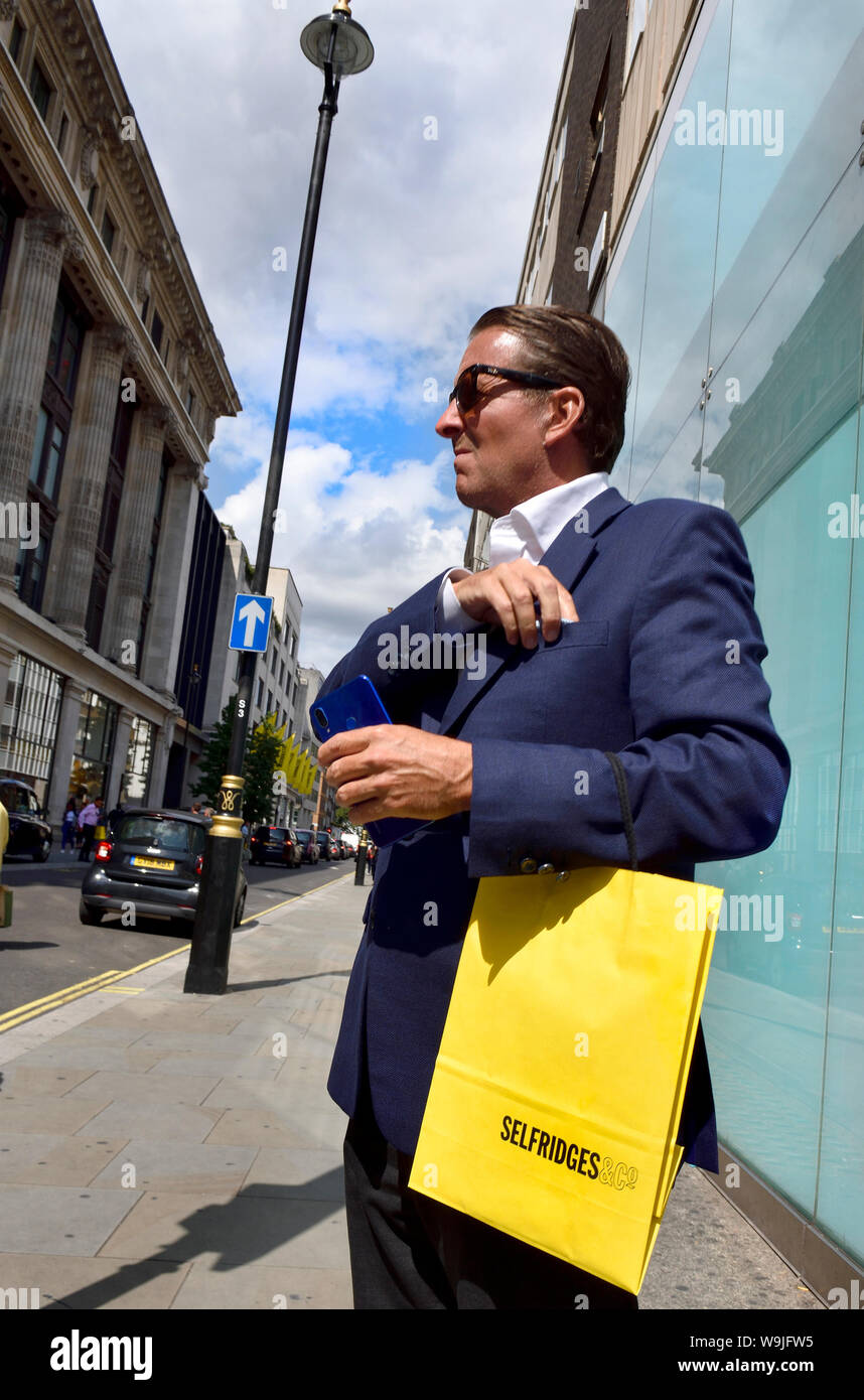 Londres, Angleterre, Royaume-Uni. L'homme bronzé bien habillés avec Selfridges housse de transport Banque D'Images