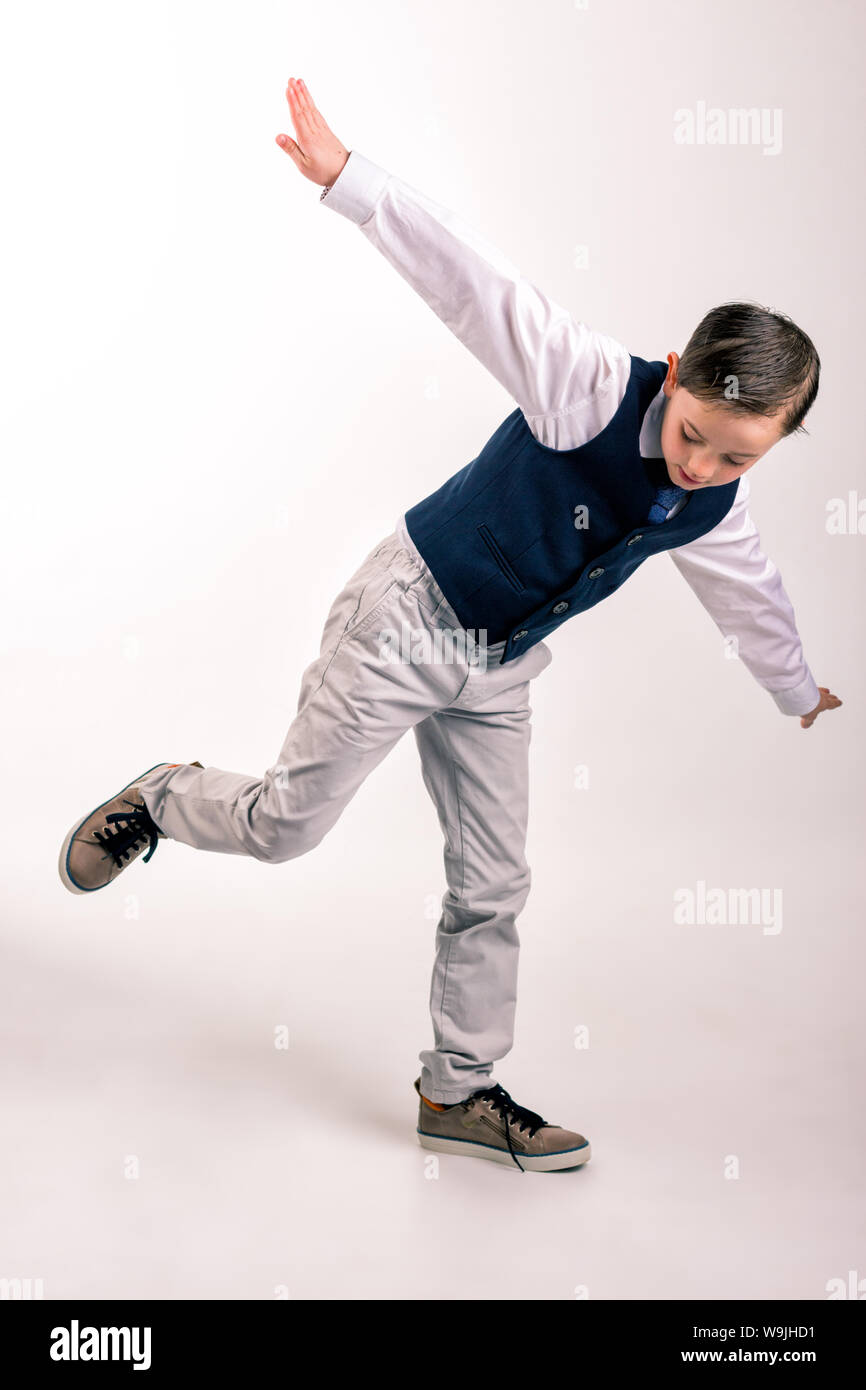 8 ans garçon habillé pour une occasion spéciale comme la communion ou la propagation de l'événement à la mains vers le bas et en soulevant la jambe droite vers le haut Banque D'Images